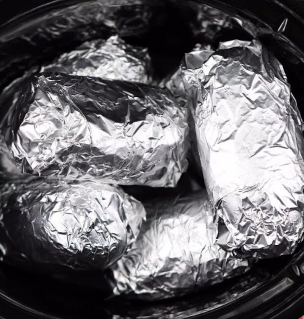 Wrap potatoes in tin foil and place in slow cooker. Enjoy this delectable outcome.